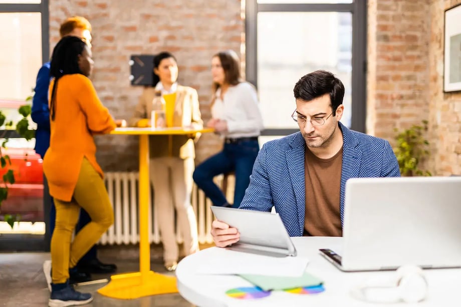 Business professional reviewing tax documents in a modern Melbourne office while team collaborates in background — representing business tax and advisory services by 42 Advisory.