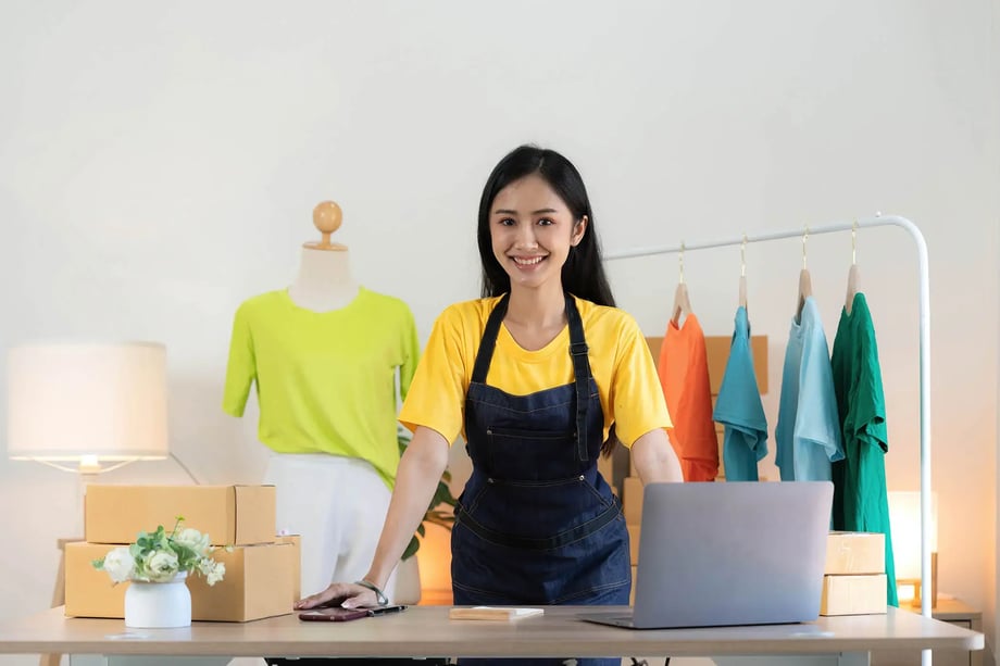 Female small business owner standing in her clothing studio with a laptop, symbolising 42 Advisory’s accounting and advisory support for startups and entrepreneurs in Melbourne.
