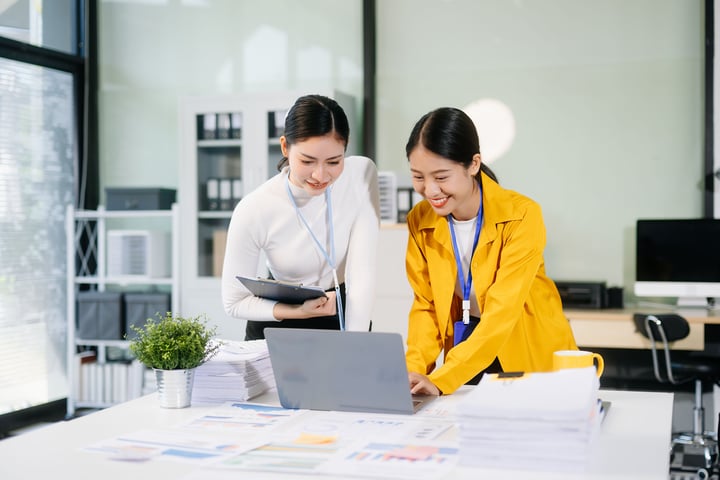 Two healthcare professionals reviewing financial documents on a laptop in a modern office setting.