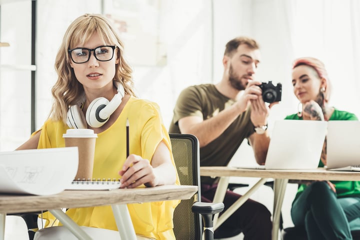 Creative professionals working with laptops and cameras in a modern office