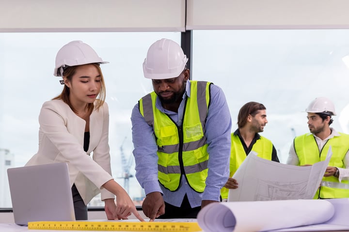Construction engineers reviewing blueprints and project plans at a building site